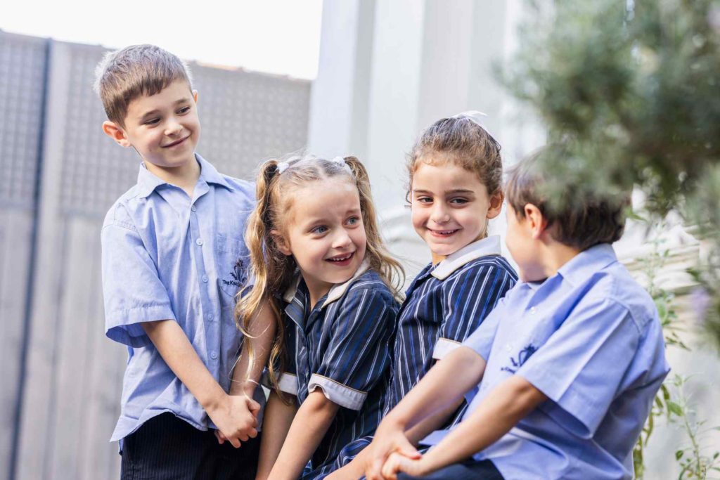 Four Prep students are wearing King David school uniform and smiling at each other. They are happy to be at school.