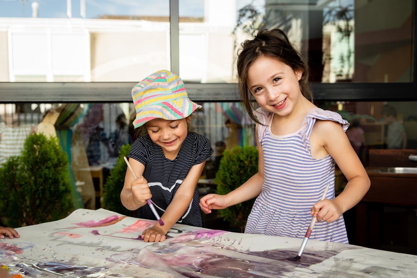 ELC students holding paintbrushes, learning through play