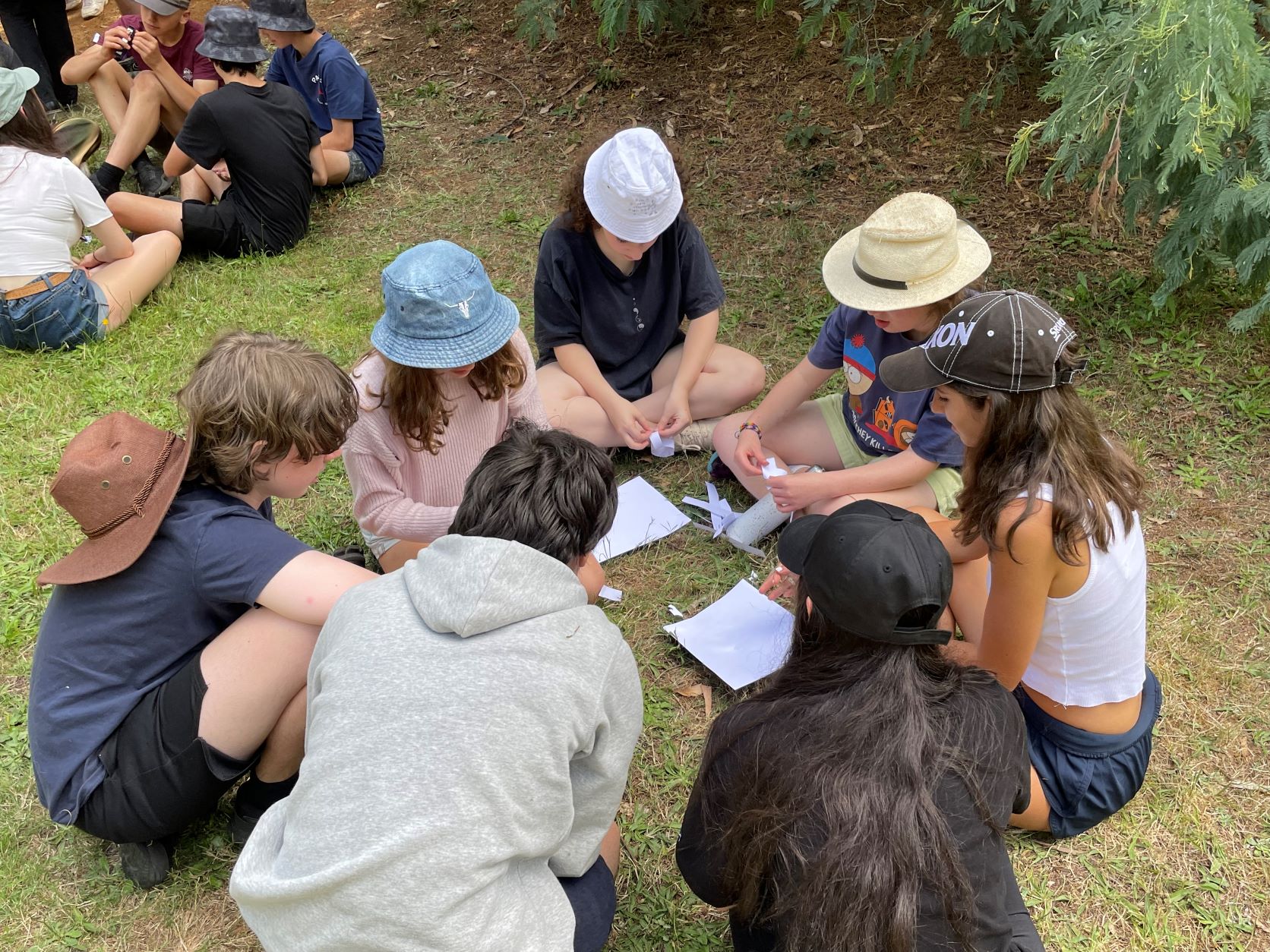 Year 10 students on camp sitting in a circle holding paper in their hands learning leadership skills