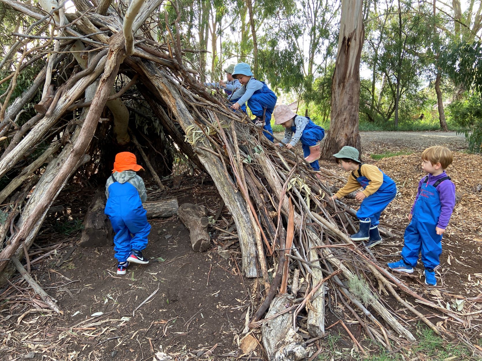 Early learners play on a teepee as part of bush kinder