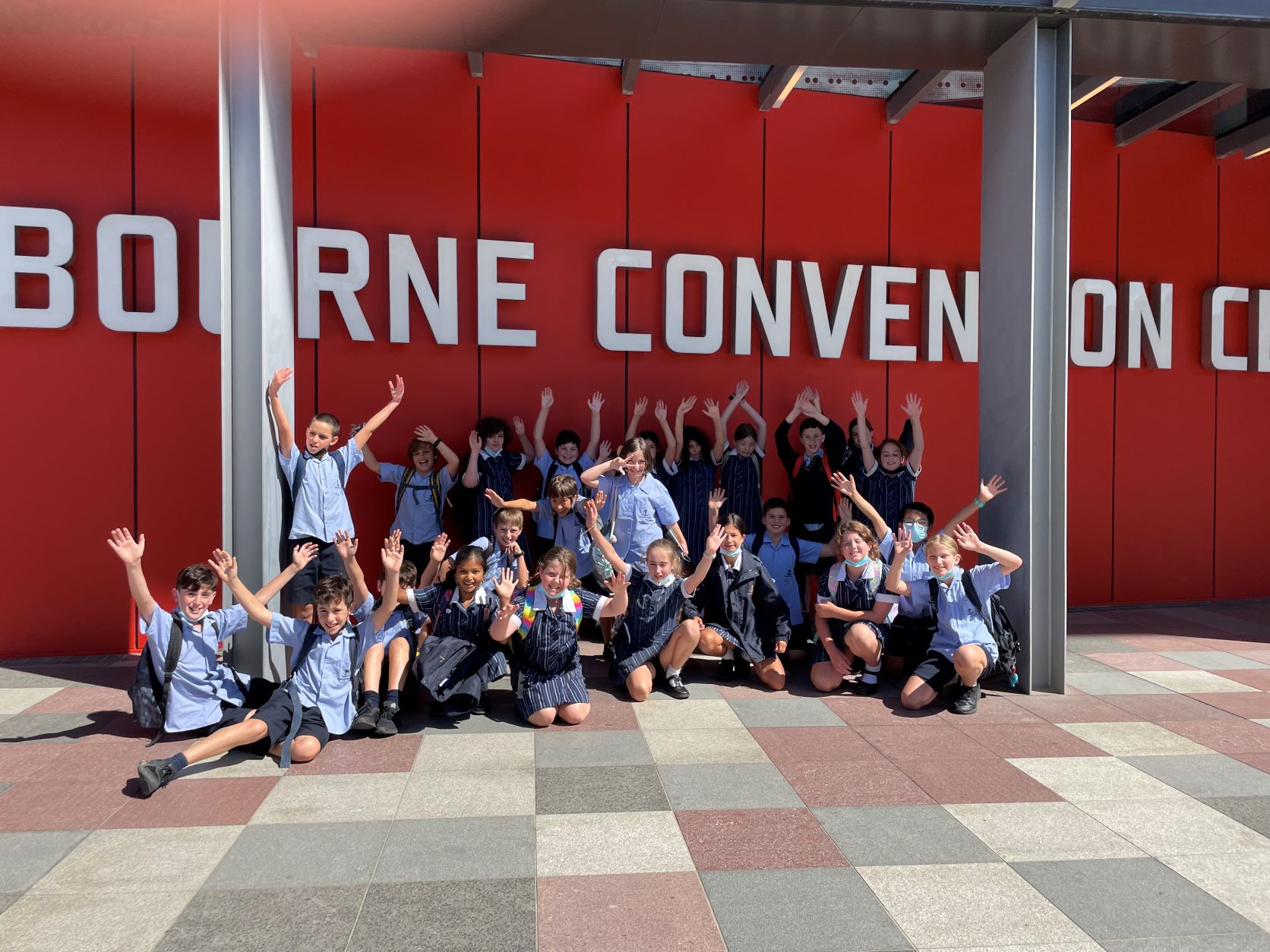 Year 5 students are in a group outside of the convention centre, waving as they attend a workshop on leadership