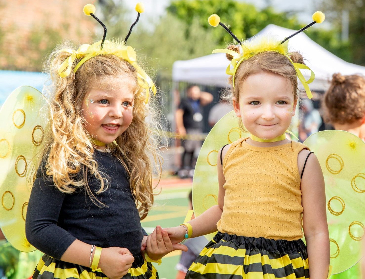 Two ELC students wearing bee costumes for Purim look at the camera