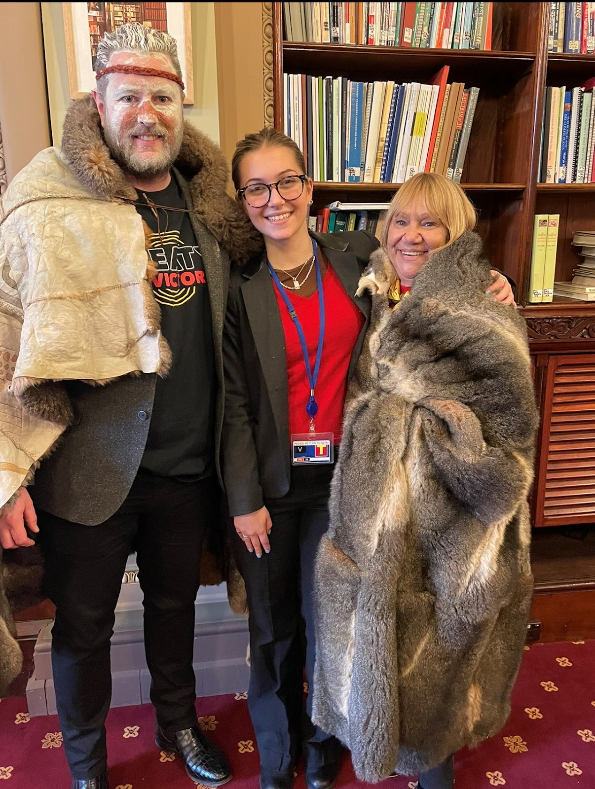 Year 10 student is in the middle of two Kulin Nation representatives, each wearing possum furs and smiling at the camera