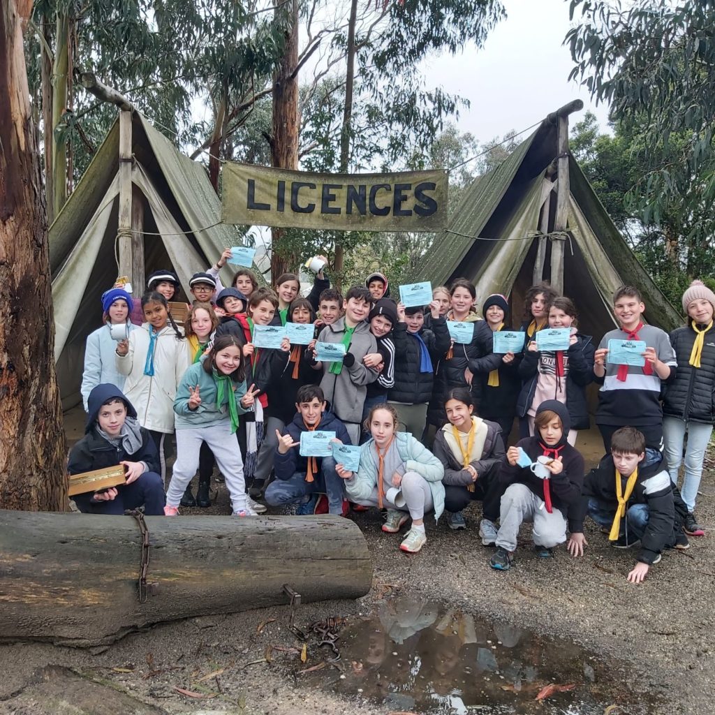 Year 5 students are in front of two old fashioned tents, they are holding mining licenses and smiling at the camera.
