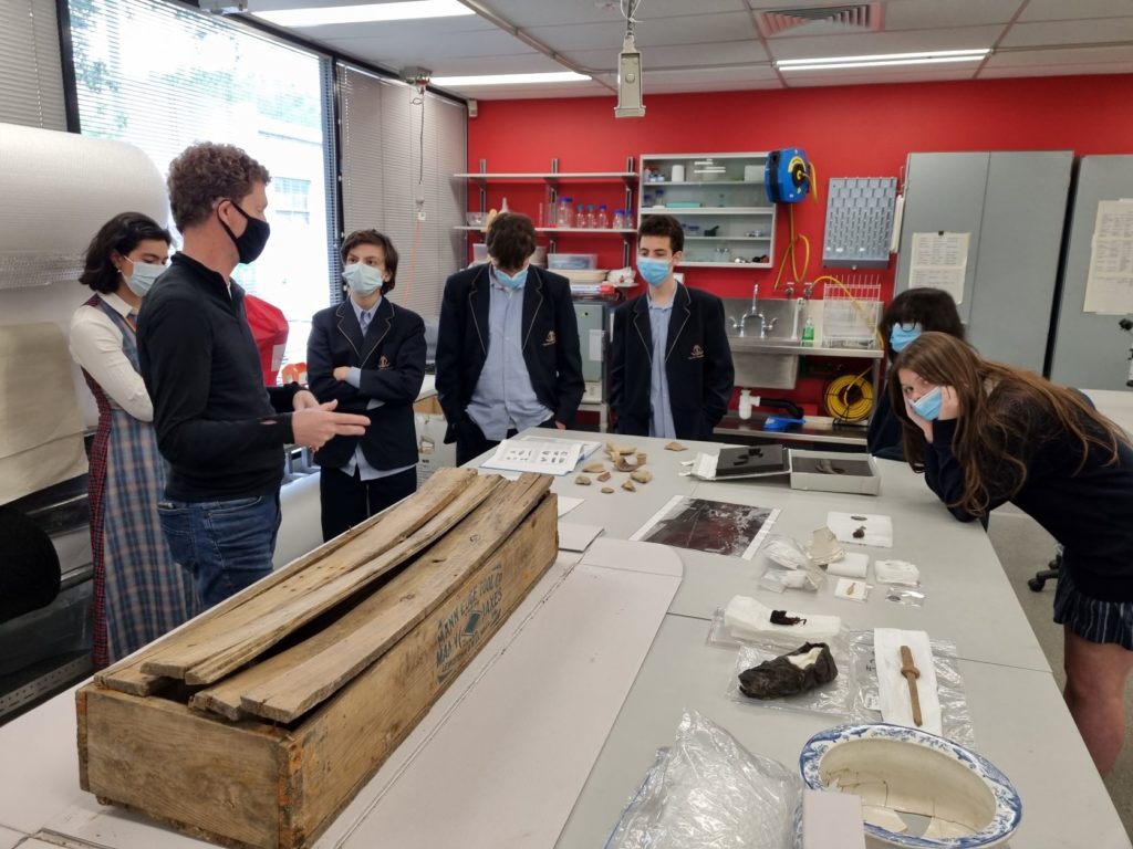 Students are gathered around a very old box - perhaps a coffin - at the archives of Heritage Victoria