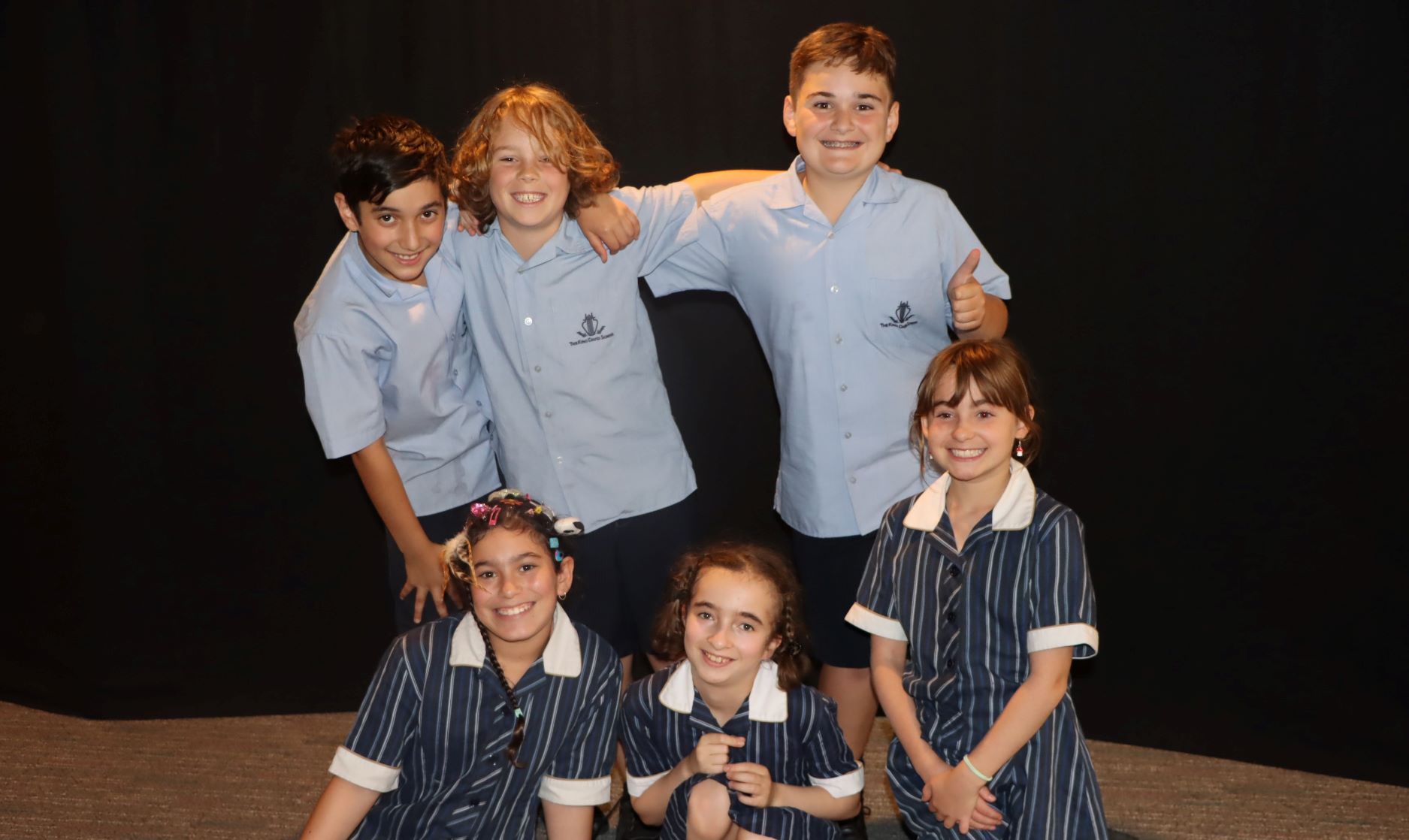 Six Year 5 students have their arms around each other. They are looking at the camera and smiling. They have just received their leadership groups.