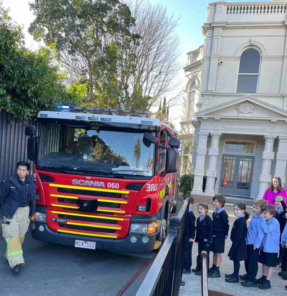 A fire truck is parked at our Dandenong road Junior School campus. Year 1 students stand next to the truck about to learn about fire safety and fire fighters