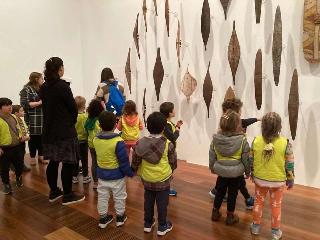 ELC students look up at First Nations art and fishing traps together.