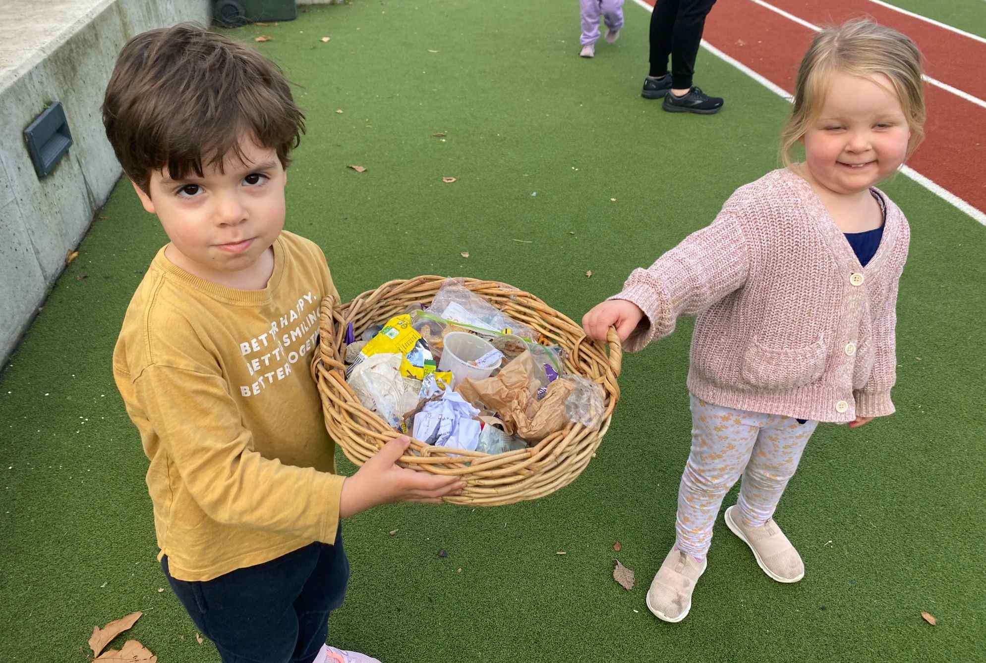 Two ELC students are holding a basket of rubbish they have picked up from around the school campus. They are marking World Environment Day