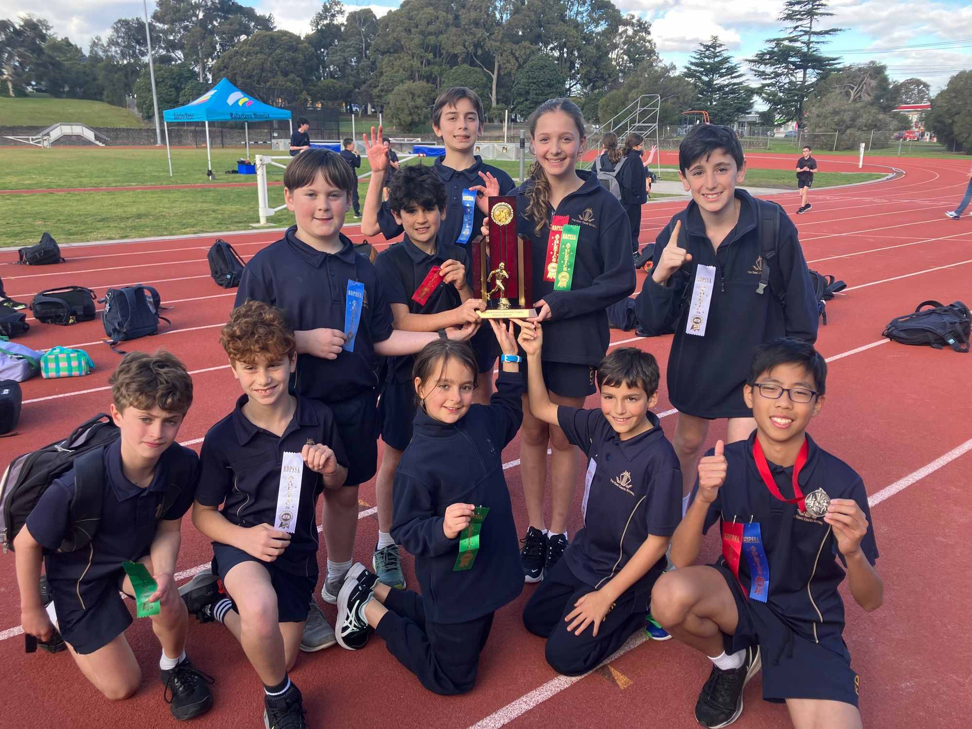 The King David Years 4-6 winners of the 2023 BDPSSA Athletics Carnival hold the trophy. They are in a group and smiling, posing with the trophy.