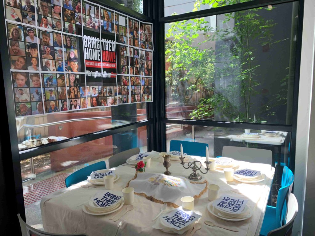 A Shabbat table is set with Challah and candles and plates ready for Shabbat dinner but there are no people at the table.