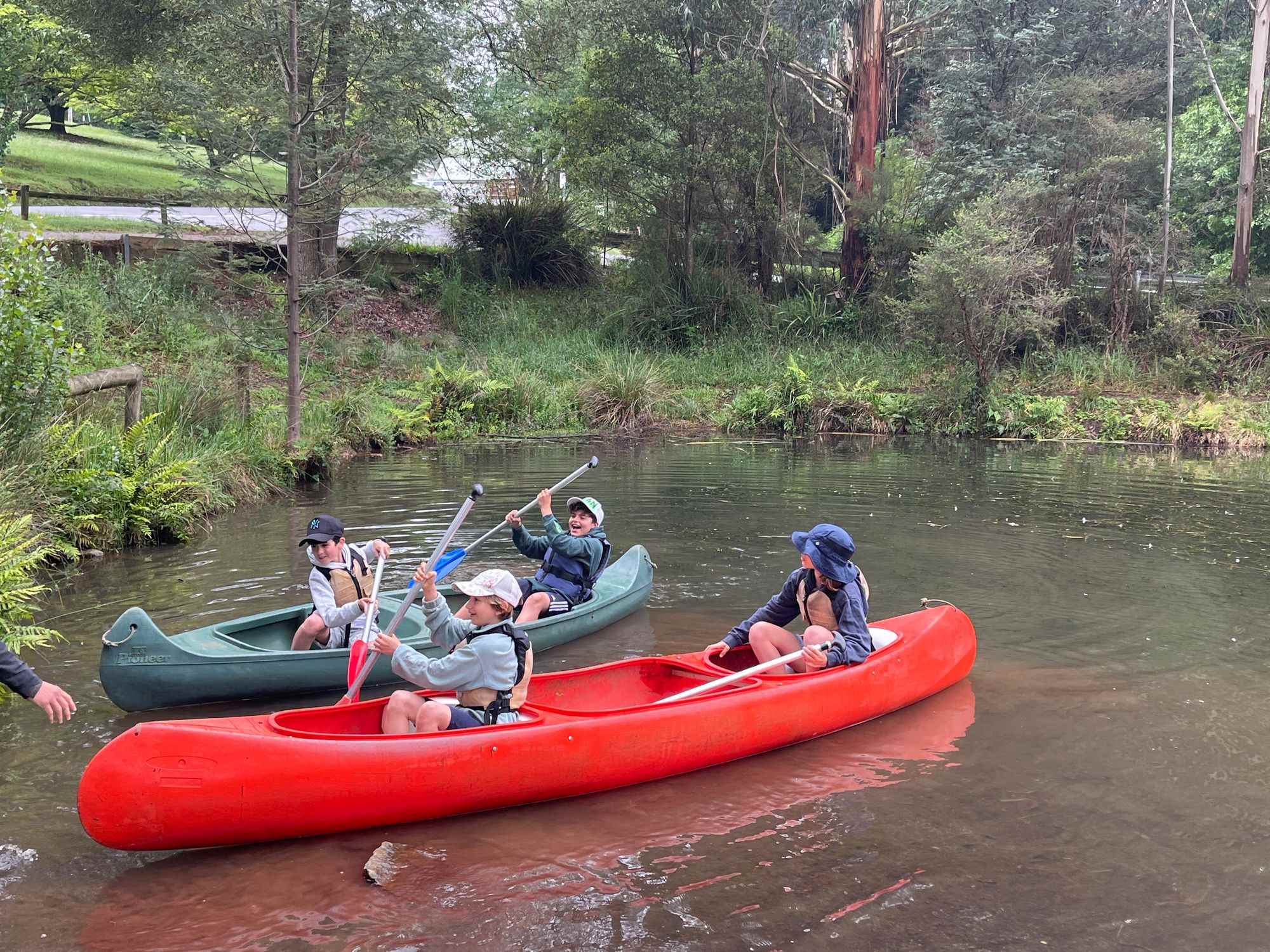 Year 4 students are in a red canoe and a green on the Yarra river.