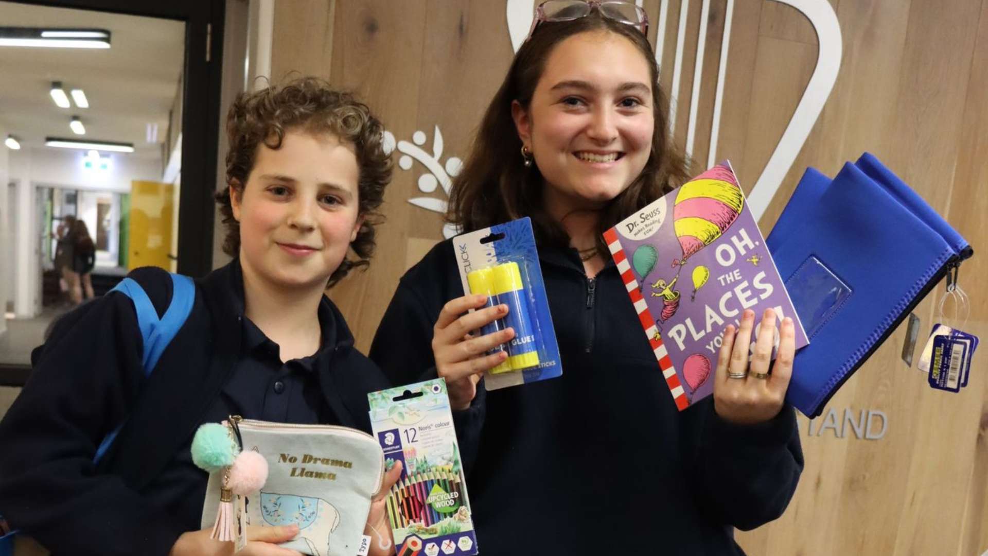 Two Middle School students hold up new stationery that students have collected for displaced families in Israel.