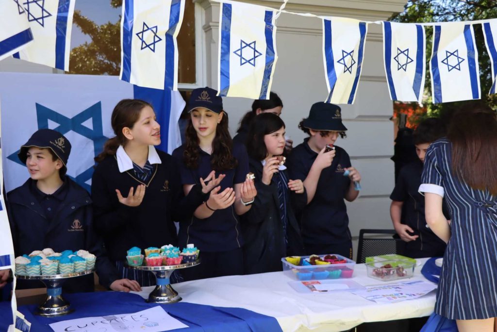 Year 7 students stand behind piles of cupcakes and biscuits ready to be sold to student to raise money for Israel.