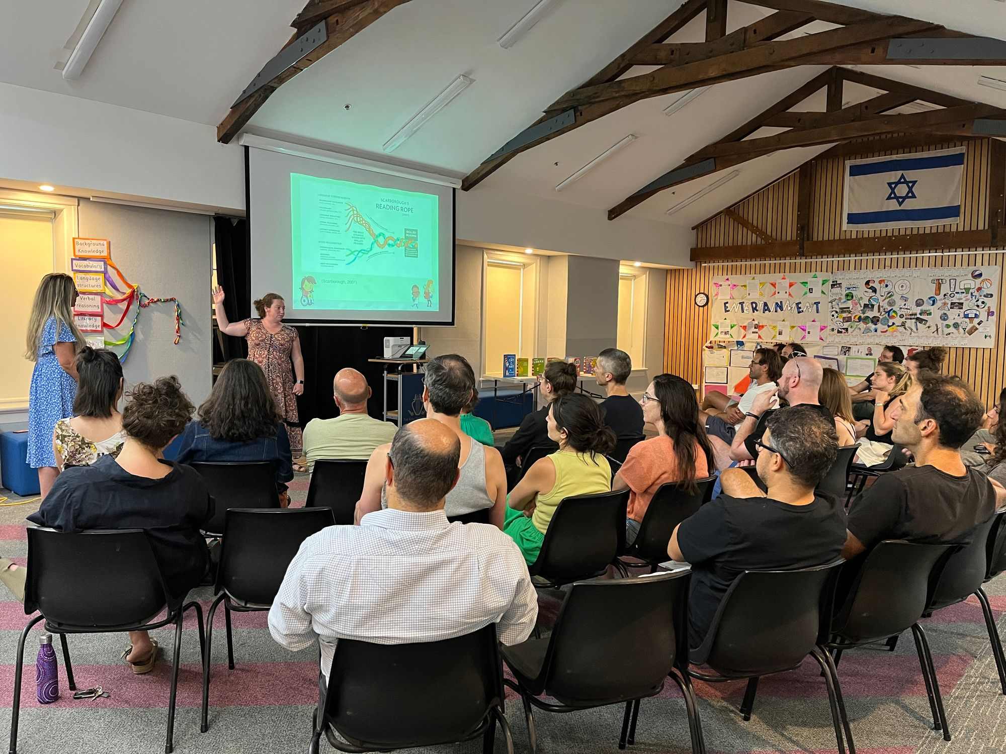 Prep teachers are at the front of the hall, presenting to parents of Prep children about how they can help their children learn how to read.