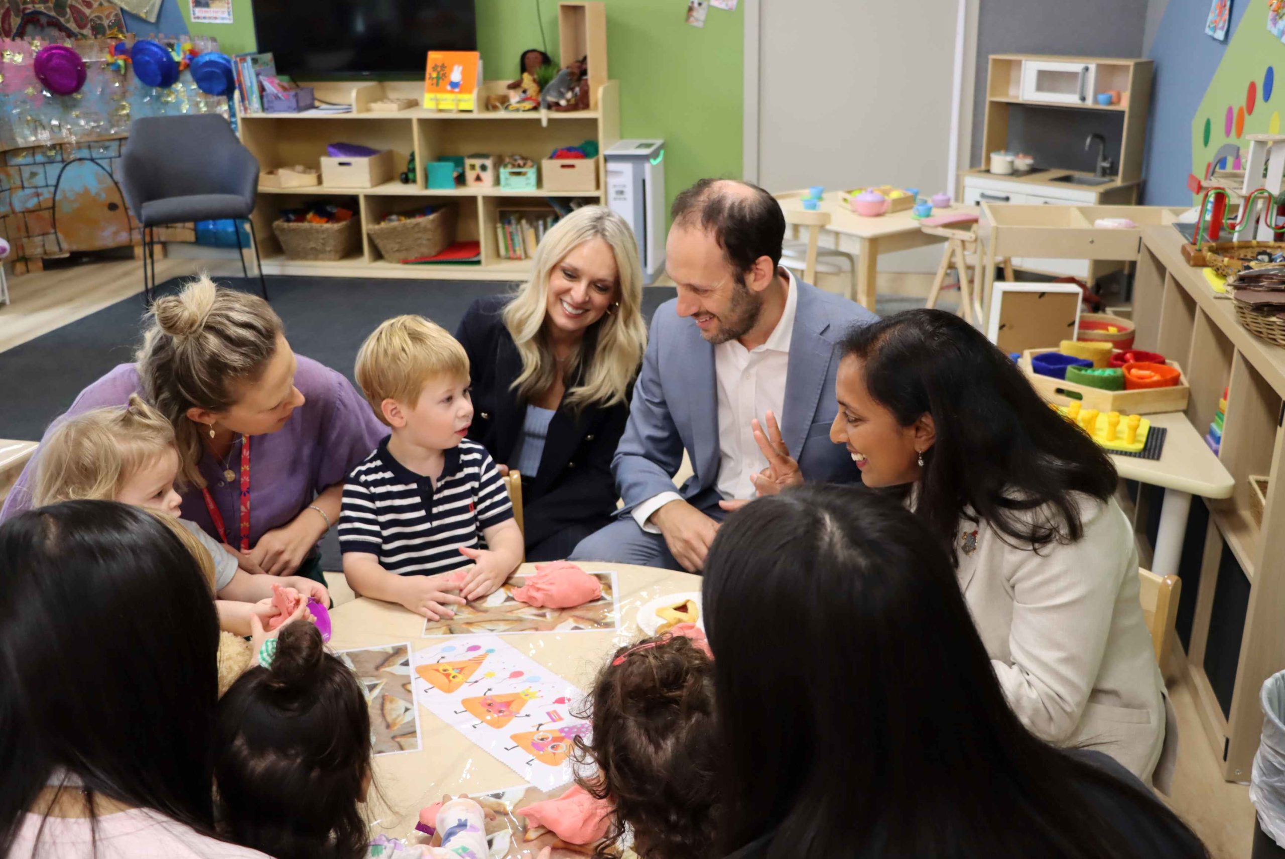 Dr Michelle Ananda-Rajah, Member for Higgins, with Principal Marc Light, Director of the ELC Marina, and teacher Amy, play with children at a table. They are celebrating the official opening of Gan Chitah, the new ELC room.