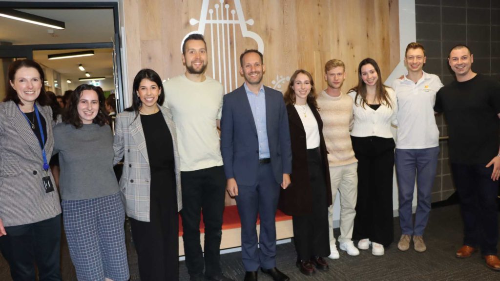 Nine alumni pose with Careers Advisor Nicki Goodrich and Principal Marc Light. They are looking at the camera and smiling. they have returned to school to give students career pathway advice.
