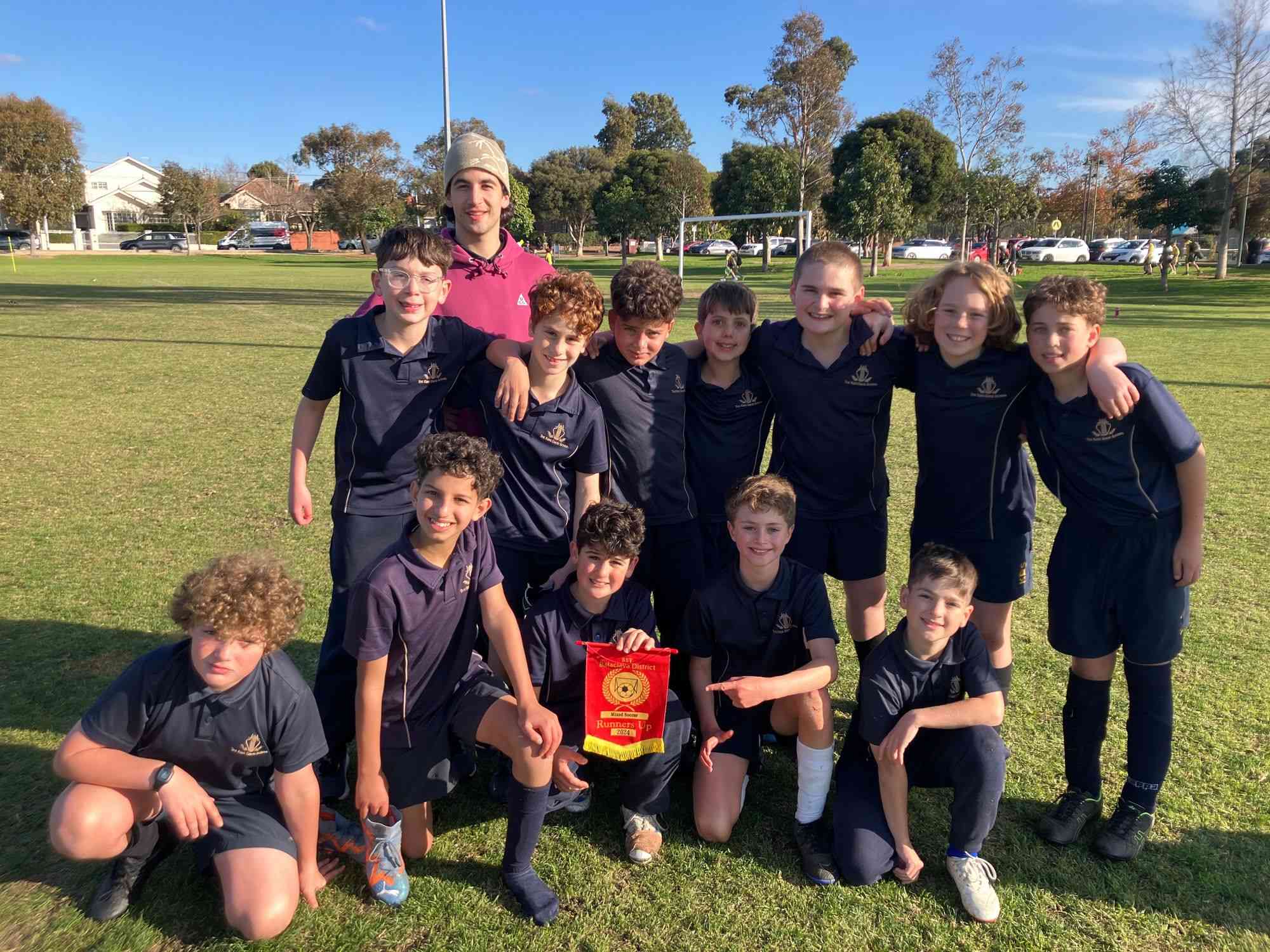 Years 5 and 6 boys soccer team huddle together looking at the camera after becoming the runners up in the BDPSSA Winter round robin competitoin.