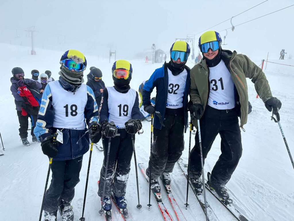 Four King David students are in ski clothes, including ski goggles and helmuts. They are on skis and holding ski poles. They are at Mt Buller in the snow about to compete in the Jewish Interschools Skiing competition.