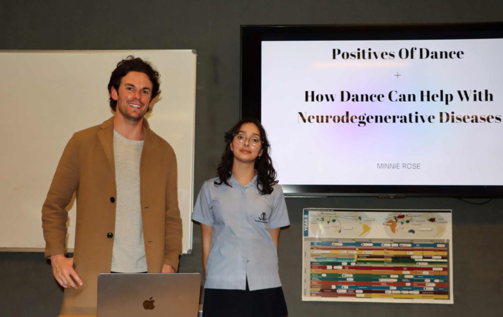 Year 8 student Minnie is with teacher Adi - Minnie has just presented her 'passion project'. Behind her is a screen that says 'how dance can help with neurodegenerative diseases'