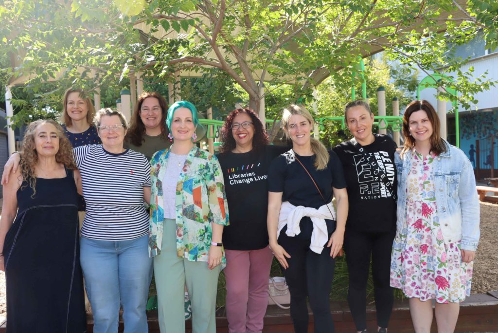 Members of the KDSPA pose outside of the 2024 AGM. They are wearing casual colourful clothes and smiling.