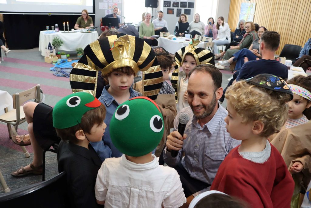 Marc Light is with ELC students at their seder. Some students are dressed as frogs, others are dressed as Pharoahs. They are learning about Pesach through holding a seder with their families.