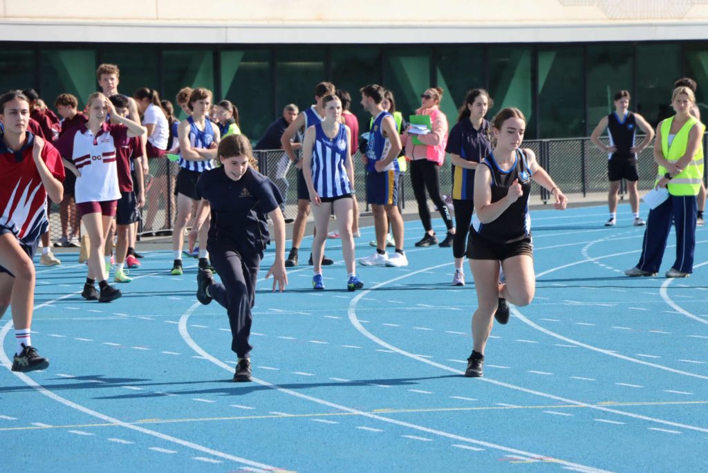 Year 7 student runs as part of a race at the EISM Athletics Carnival. She is wearing The King David School sports uniform.