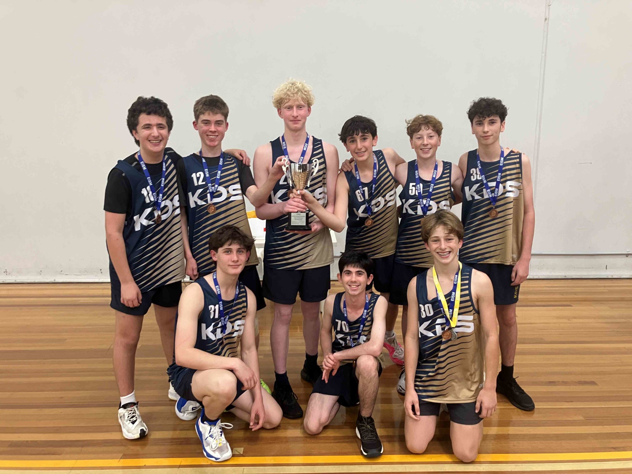 Our Years 8-9 Boys' Basketball team are holding the trophy after they won the EISM Grand Final. They are happy.