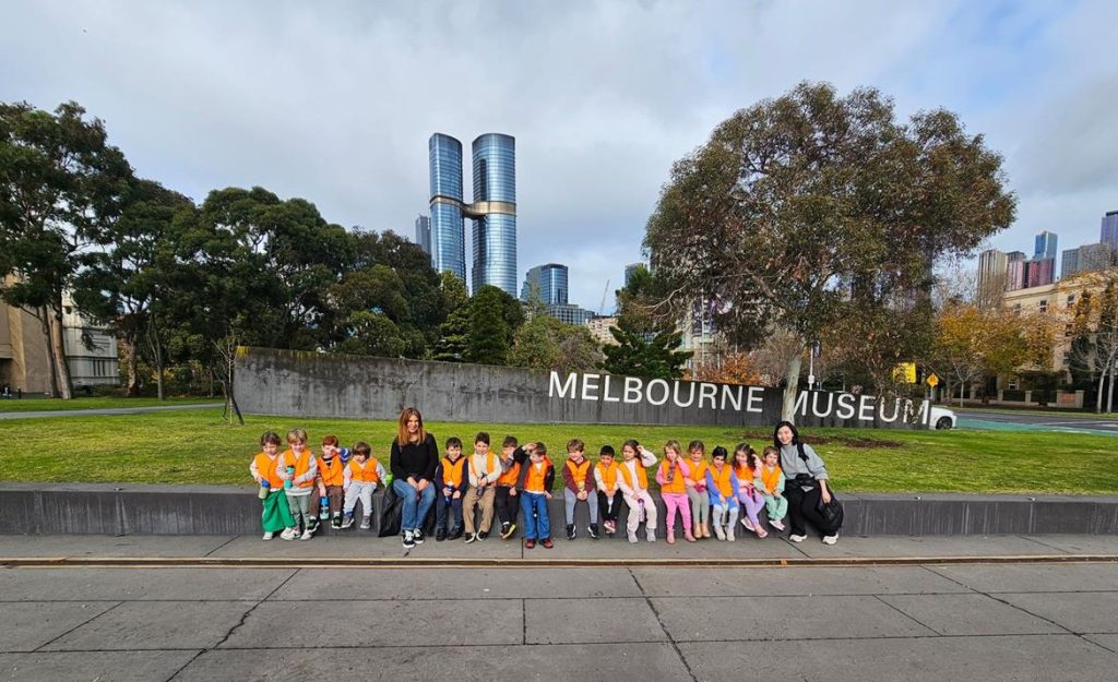 The children of Gan Tamar are outside of the Melbourne Museum. They are wearing orange hi-vis vests so they do not get lost.