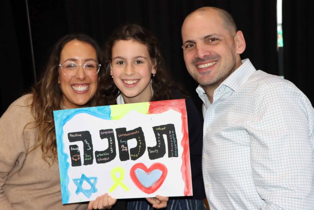 Two parents smile with their Year 4 child -they are celebrating our Hebrew names.