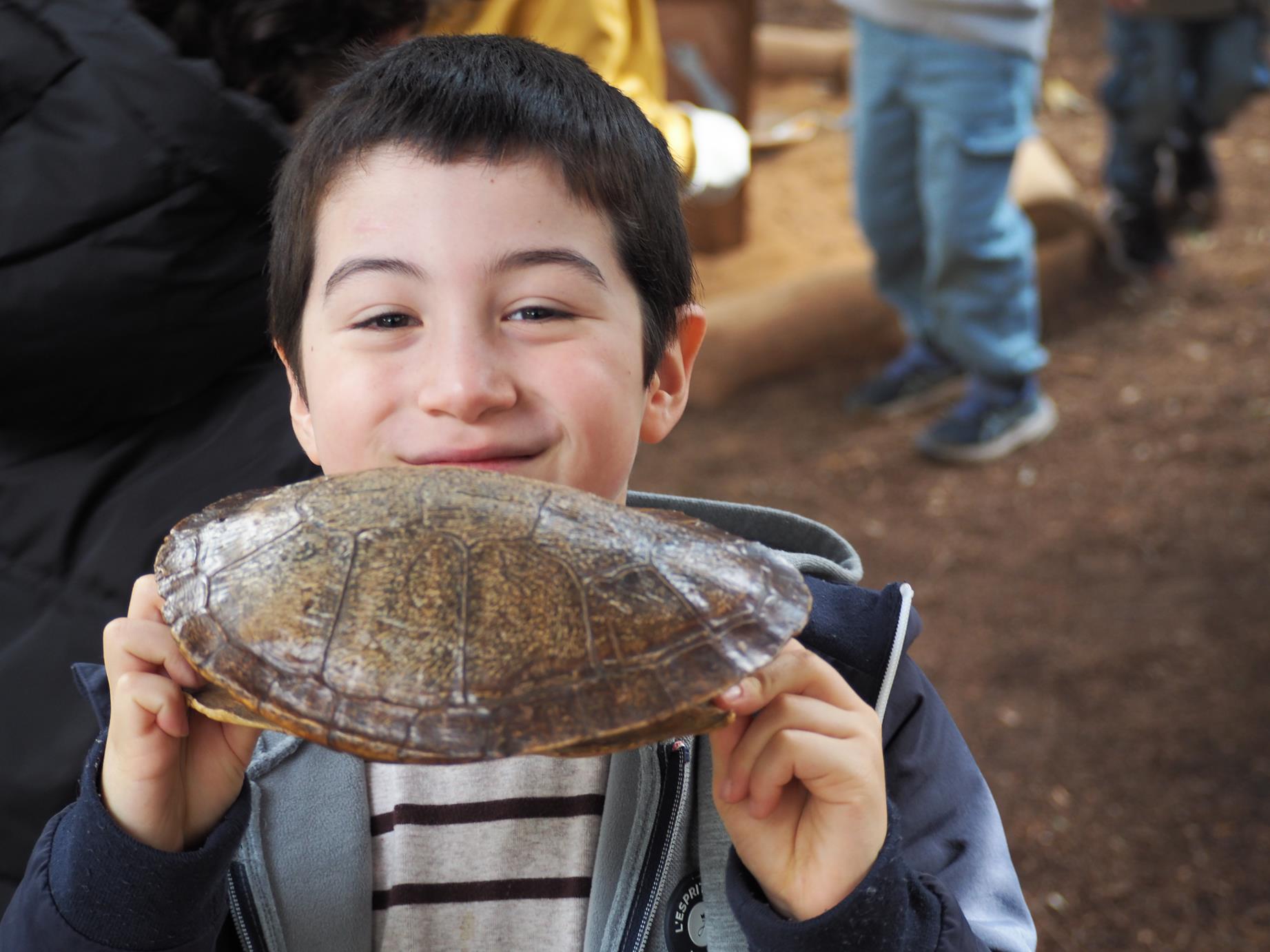 An excited Prep student holds the shell of a turtle or tortoise. He is happy to be learning at the Zoo.