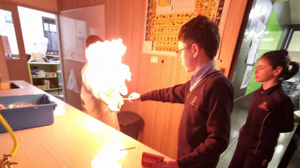 Middle School students undertake an experiment with fire for Science Week. One student appears to be touching a large flame.