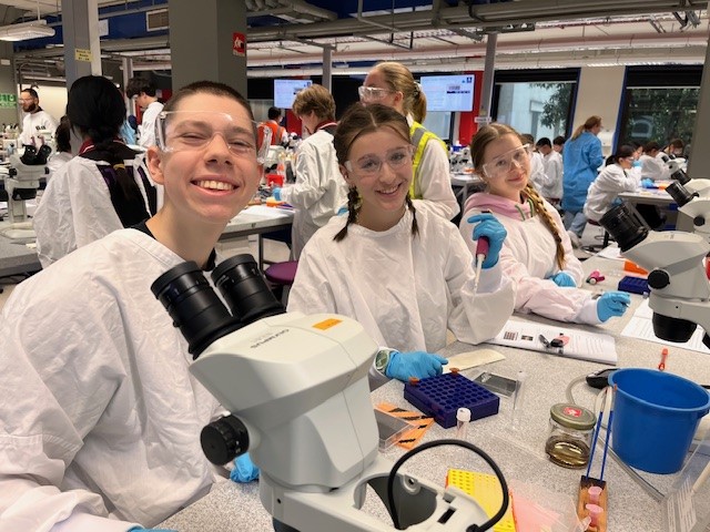 Year 12 VCE Biology students are wearing white lab coats and have microscopes in front of them. They are excited because they are at the University of Melbourne applying biological concepts.