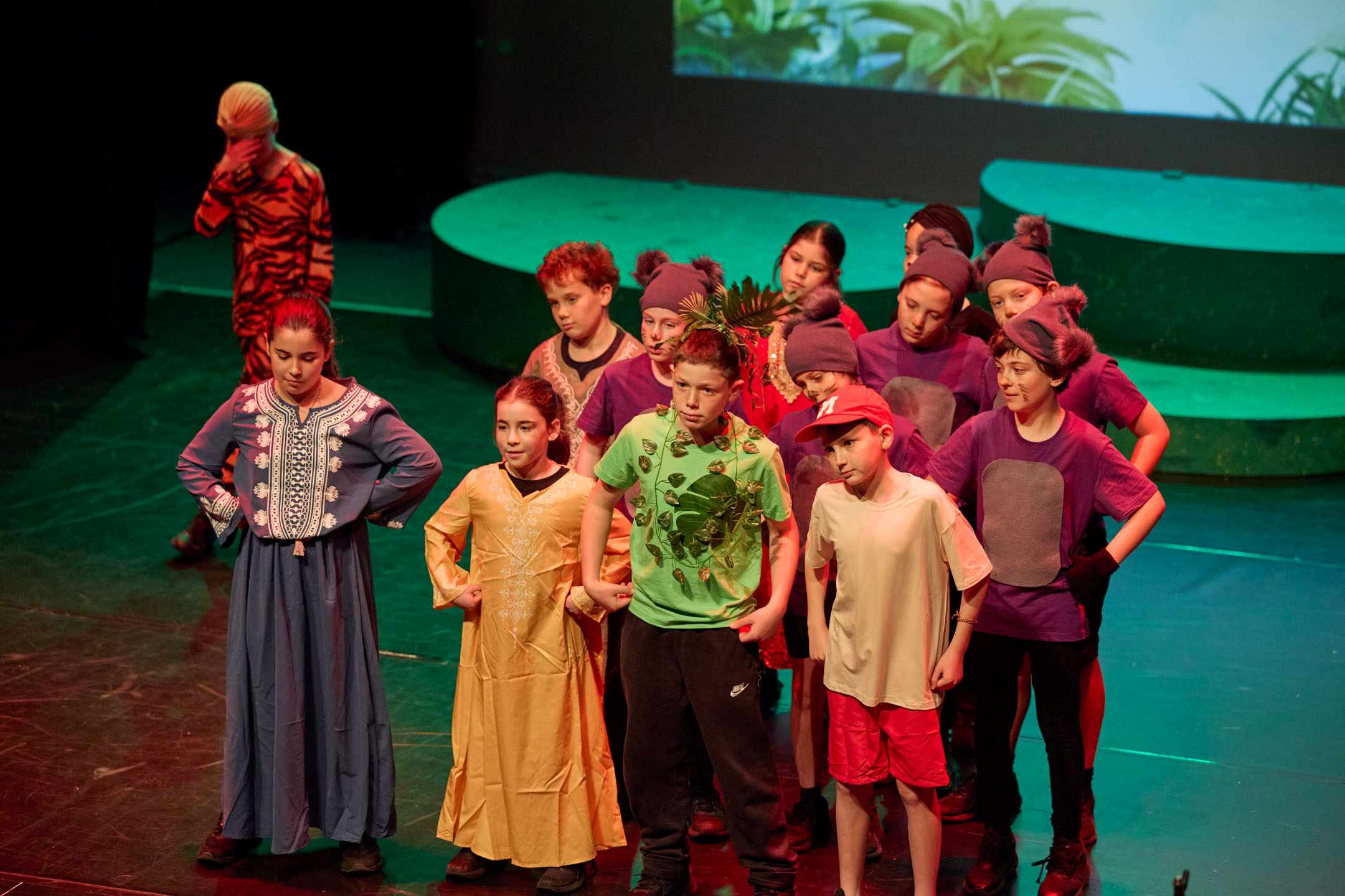 Years 3-5 students are in colourful costumes - they are on stage performing in the Years 3-5 production of The Jungle Book.