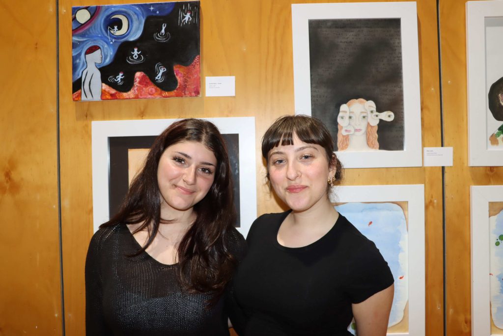 Two VCE students pose in front of their Visual Arts works. They are proud.