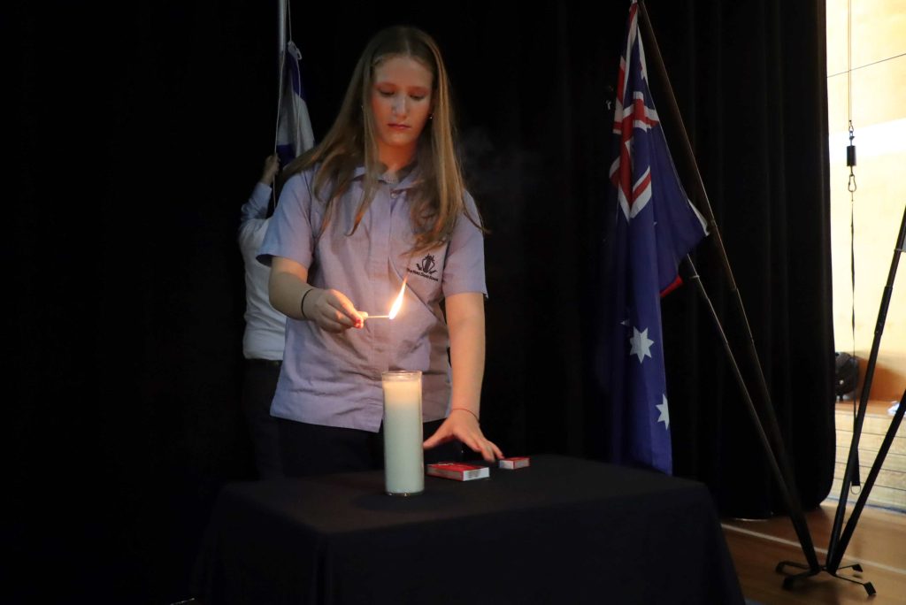 A Year 8 student lights a memorial candle to commemorate Oct 7.