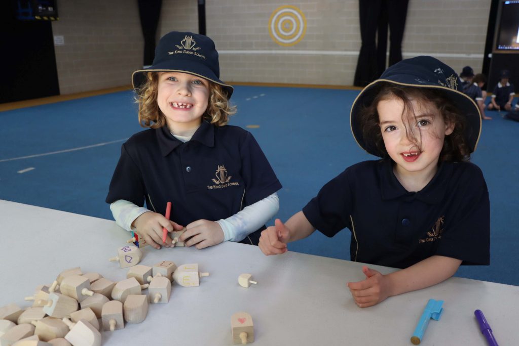 Two Prep students are holding Svivon, Dreidels - they are decorating them before the tournament.
