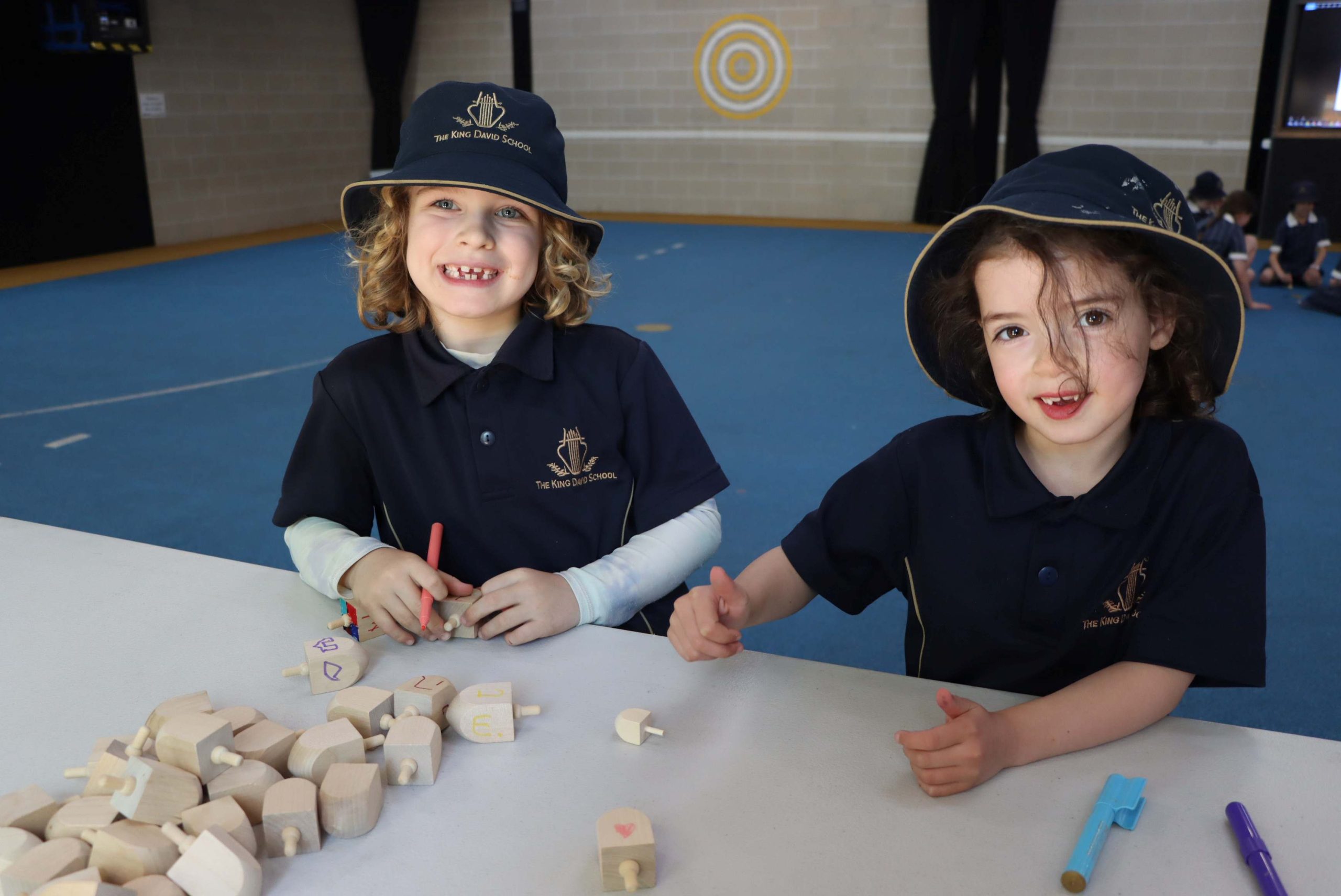 Two Prep students are holding Svivon, Dreidels - they are decorating them before the tournament.