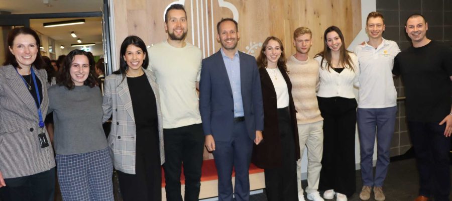 Nine alumni pose with Careers Advisor Nicki Goodrich and Principal Marc Light. They are looking at the camera and smiling. they have returned to school to give students career pathway advice.