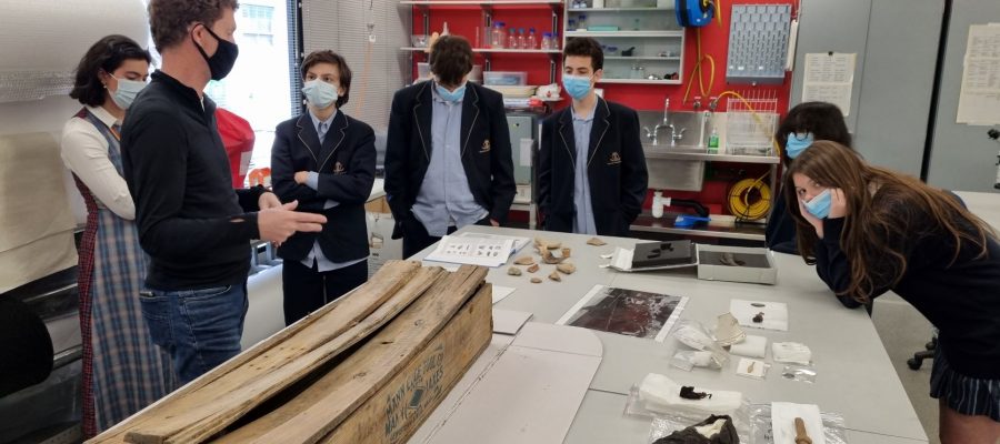 Students are gathered around a very old box - perhaps a coffin - at the archives of Heritage Victoria