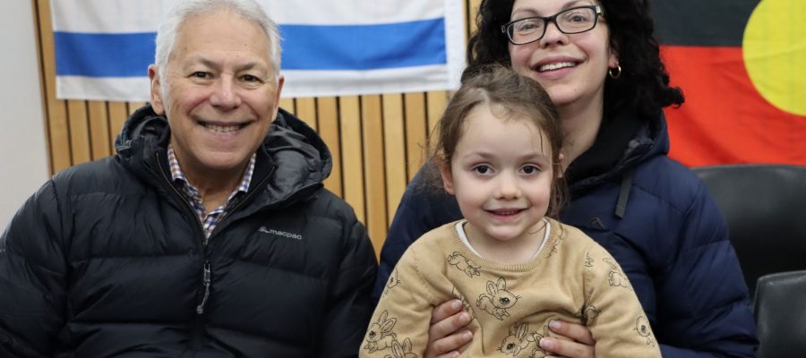 A grandfather, mother and ELC student are celebrating Shabbat together. They are looking at the camera and are happy.