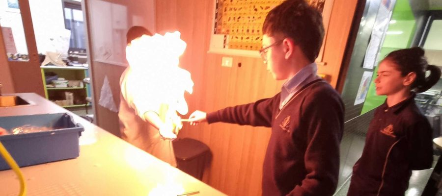 Middle School students undertake an experiment with fire for Science Week. One student appears to be touching a large flame.